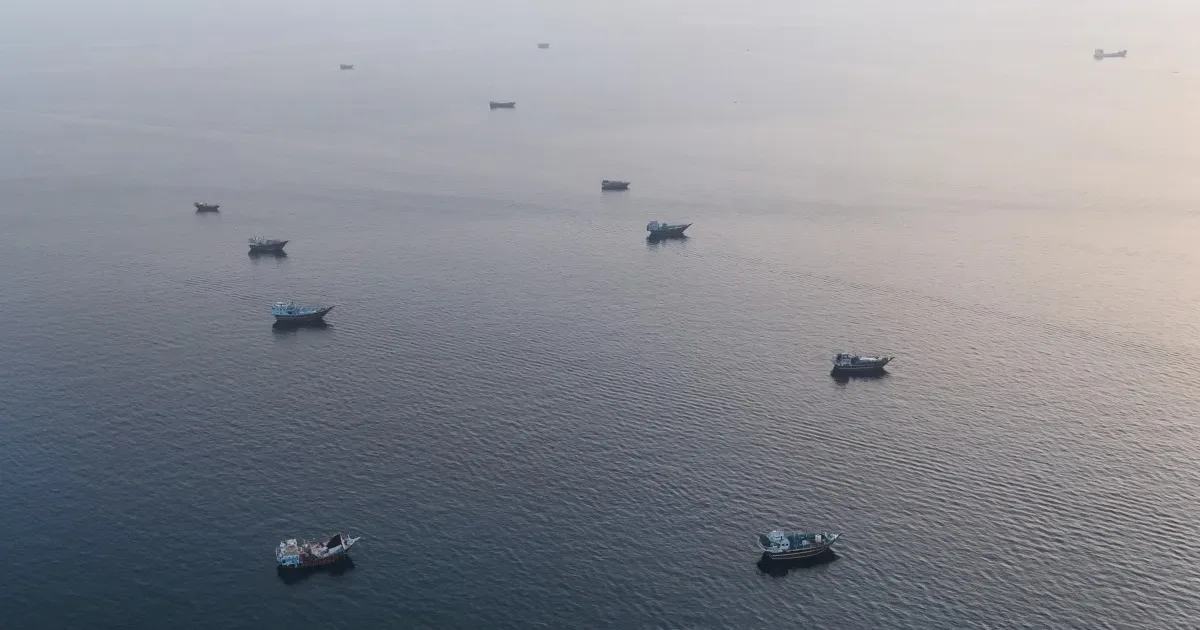 Vaporase ancorate pe o apă liniștită, simbolizând tensiuni în transportul maritim.
