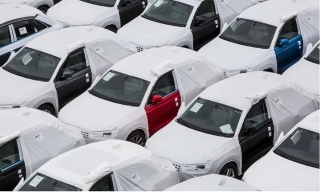 Mașini acoperite în parcarea unui dealer auto, pregătite pentru livrare.