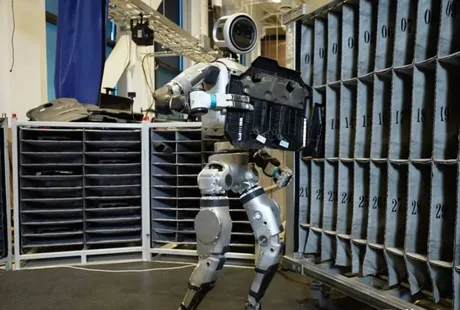 Robot umanoid Atlas manipulând obiecte într-un mediu de fabricație automatizat.