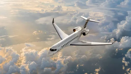 Avionul Bombardier Global 8000 zburând deasupra norilor la apus.