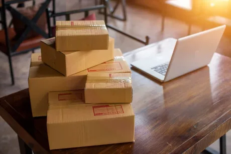Pachete de produse așezate pe o masă lângă un laptop.