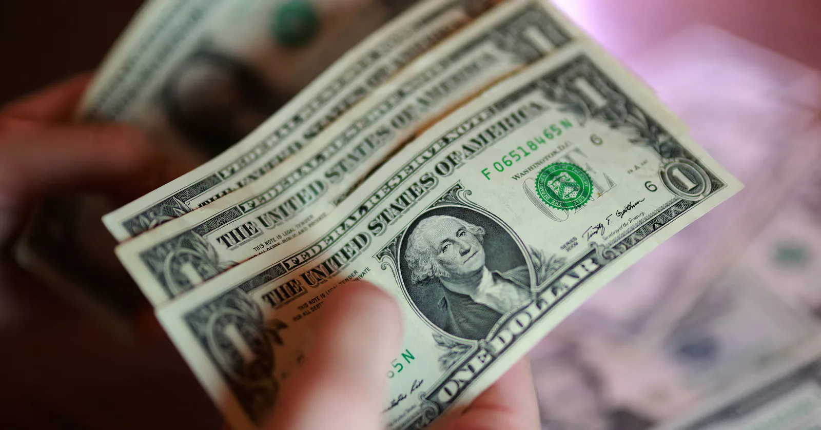 Bancnote de dolari americani în mână, simbolizând fluctuațiile valutare.