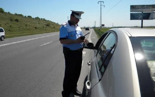 Un polițist verifică documentele unui șofer pe marginea drumului.