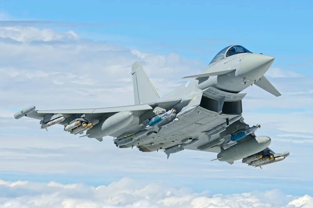 Avion Eurofighter Typhoon zburând pe un fundal de nori albi și cer albastru.