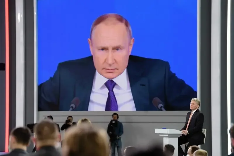 Vladimir Putin la o conferință de presă, cu un ecran mare în fundal.