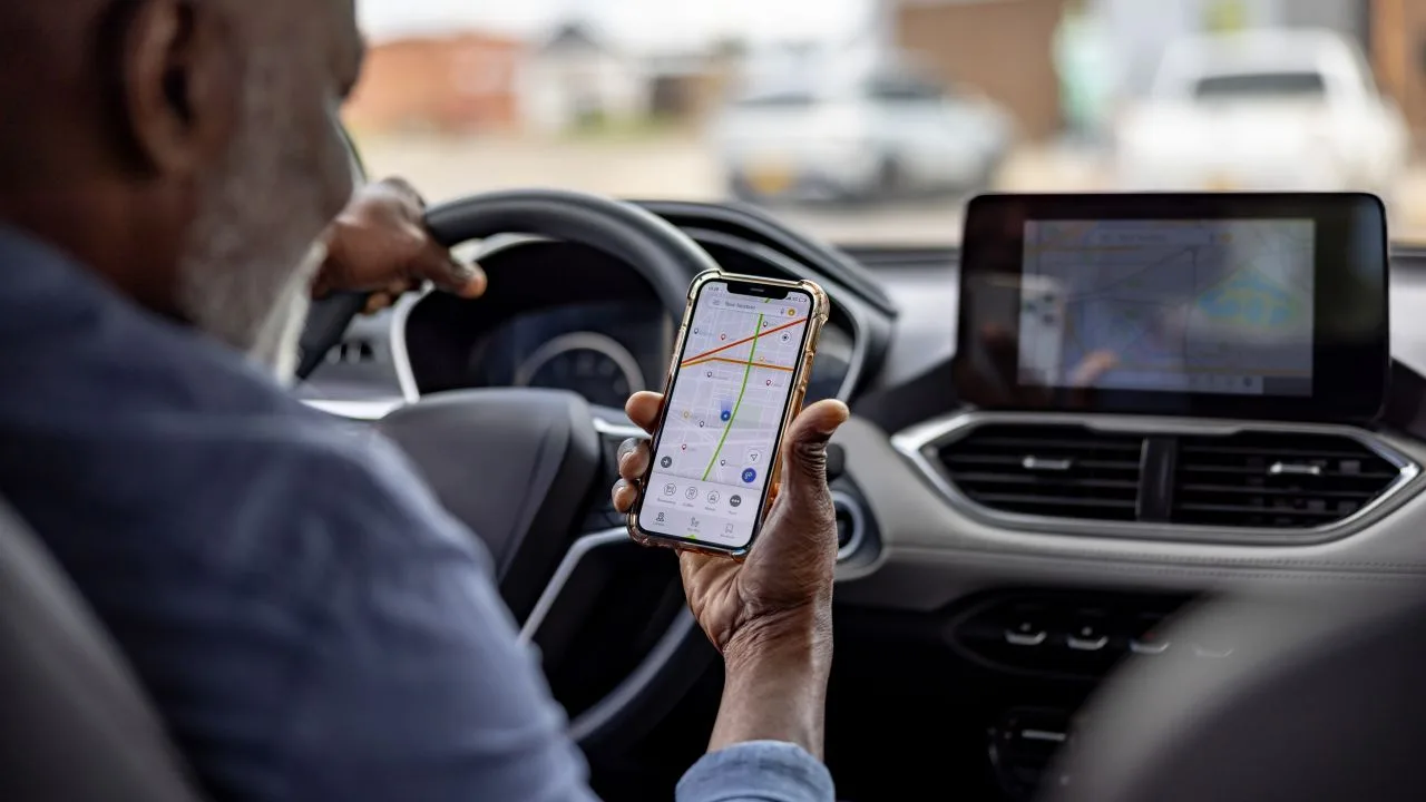 Șofer verificând aplicația Uber pe telefon în timpul unei curse.