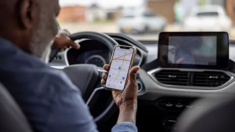 Șofer verificând aplicația Uber pe telefon în timpul unei curse.
