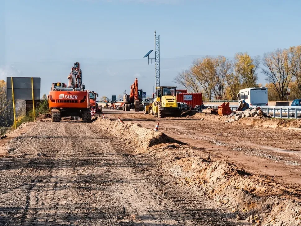 Lucrări de construcție pe un șantier, cu utilaje și echipamente diverse.