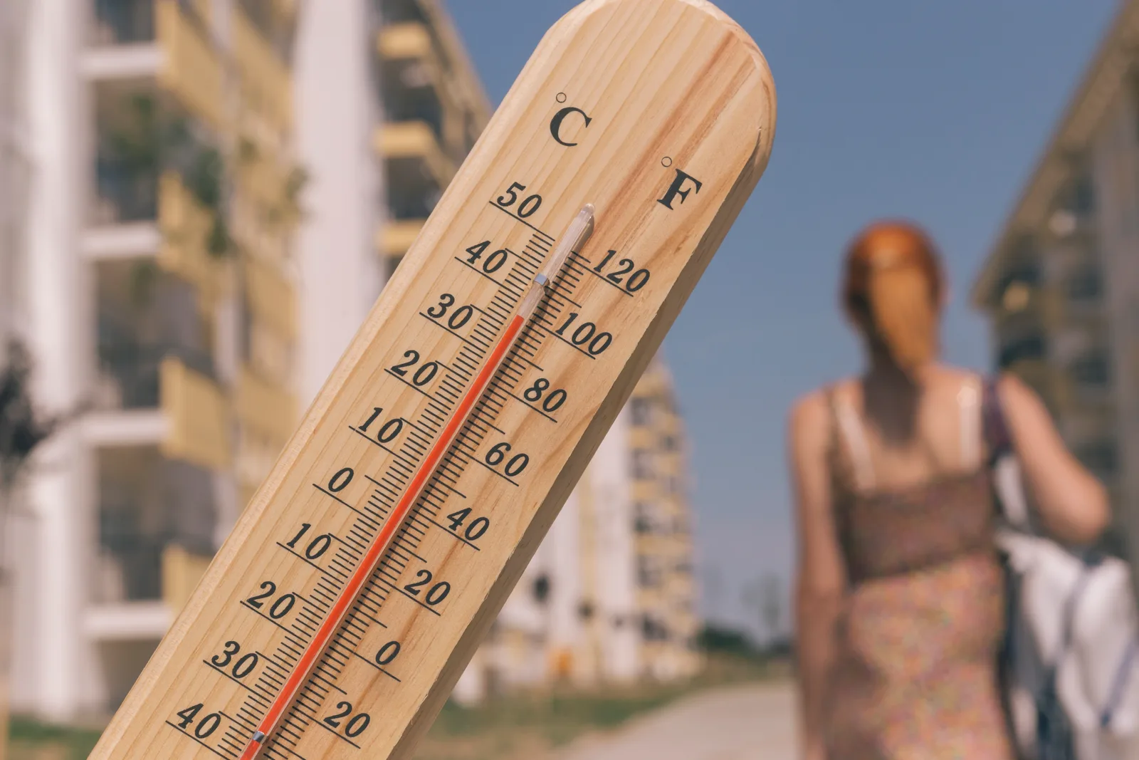 Termometru arătând temperaturi ridicate în oraș pe fundal de clădiri.
