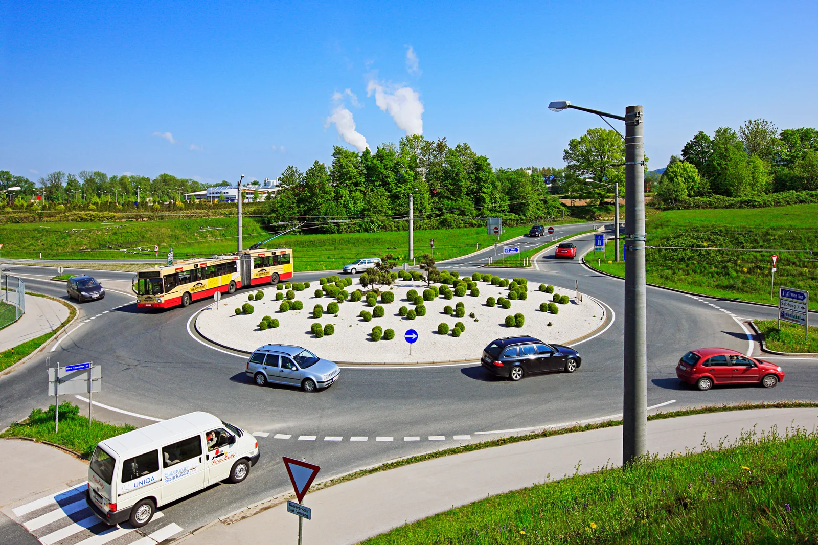Sens giratoriu cu vehicule în mișcare și semne de circulație vizibile.