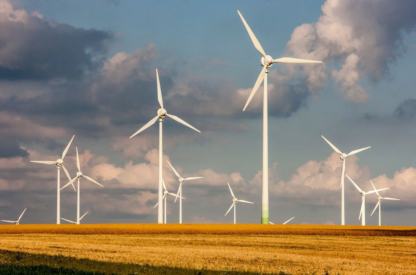 Turbine eoliene pe un câmp, simbolizând energia regenerabilă.
