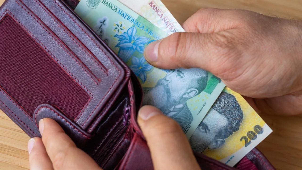 Bărbat care pune bani în portofel, simbolizând cheltuieli și economii.