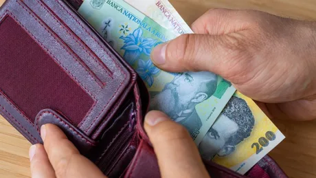 Bărbat care pune bani în portofel, simbolizând cheltuieli și economii.