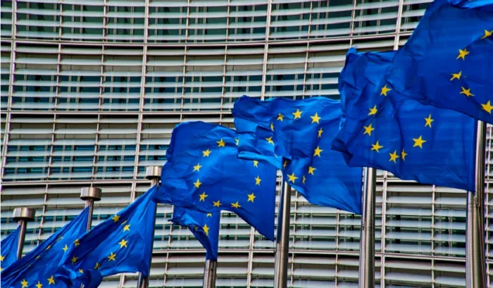 Steaguri ale Uniunii Europene fluturând în fața unei clădiri moderne.