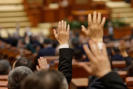 Membrii Parlamentului ridică mâinile pentru voturi în sesiune extraordinară.