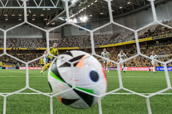 Minge de fotbal în apropierea porții, cu jucători pe teren.
