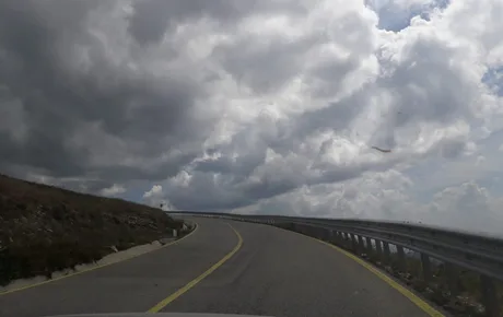 Peisaj montan pe Transfăgărășan, drum curbat și nori deasupra.