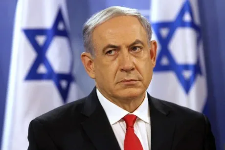 Benjamin Netanyahu exprimându-se în fața presei, steaguri israeliene în fundal.
