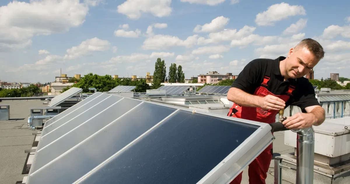 Tehnician verificând panouri solare pe acoperișuri în Germania.