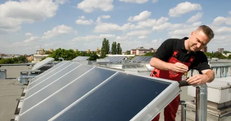 Tehnician verificând panouri solare pe acoperișuri în Germania.