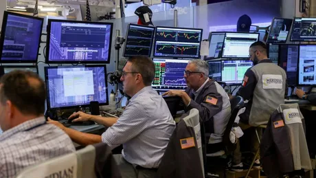 Traderi analizați piețele financiare în fața ecranelor multiple.