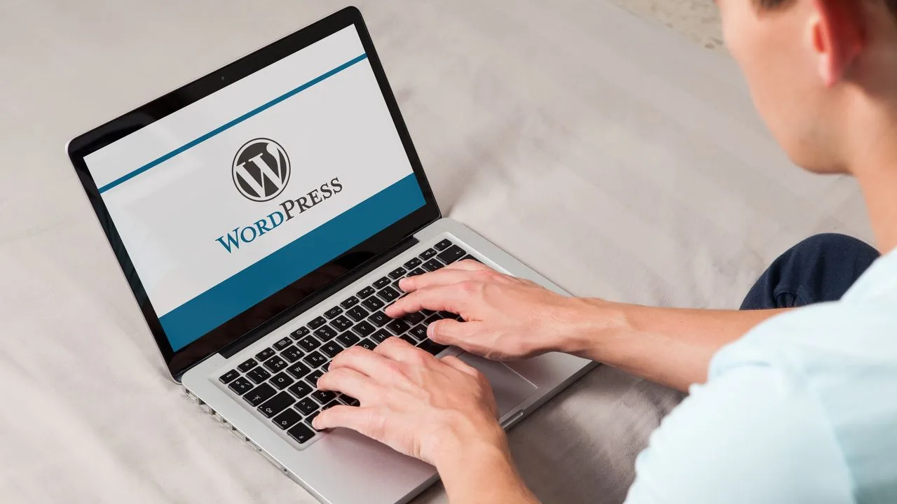 Utilizator lucrând pe un laptop cu interfața WordPress deschisă.