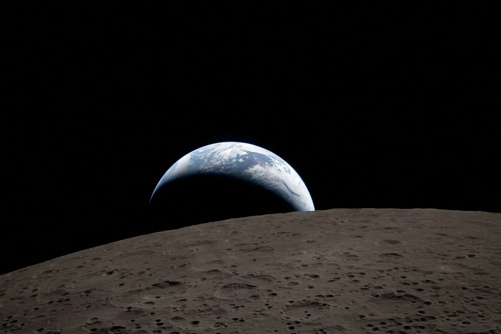 Vedere a Pământului de pe Lună, evidențiind curburile sale și suprafața lunară.
