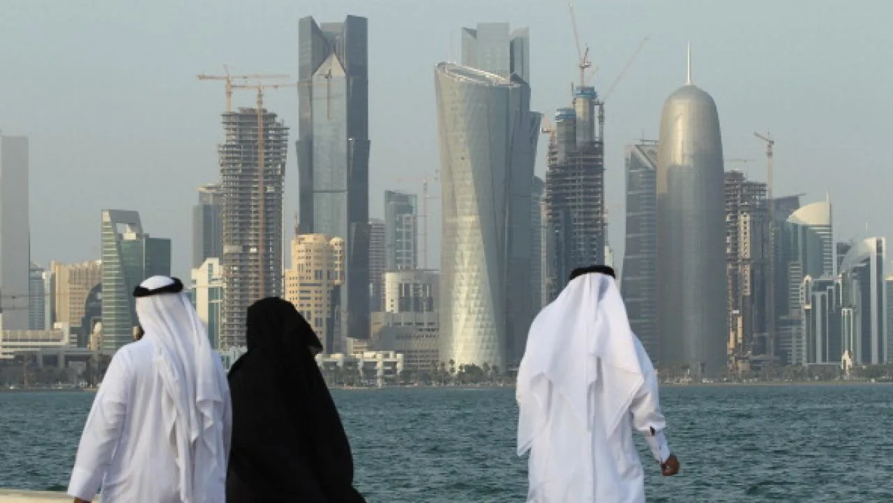 Persoane admirând peisajul urban din Qatar, cu clădiri moderne în fundal.