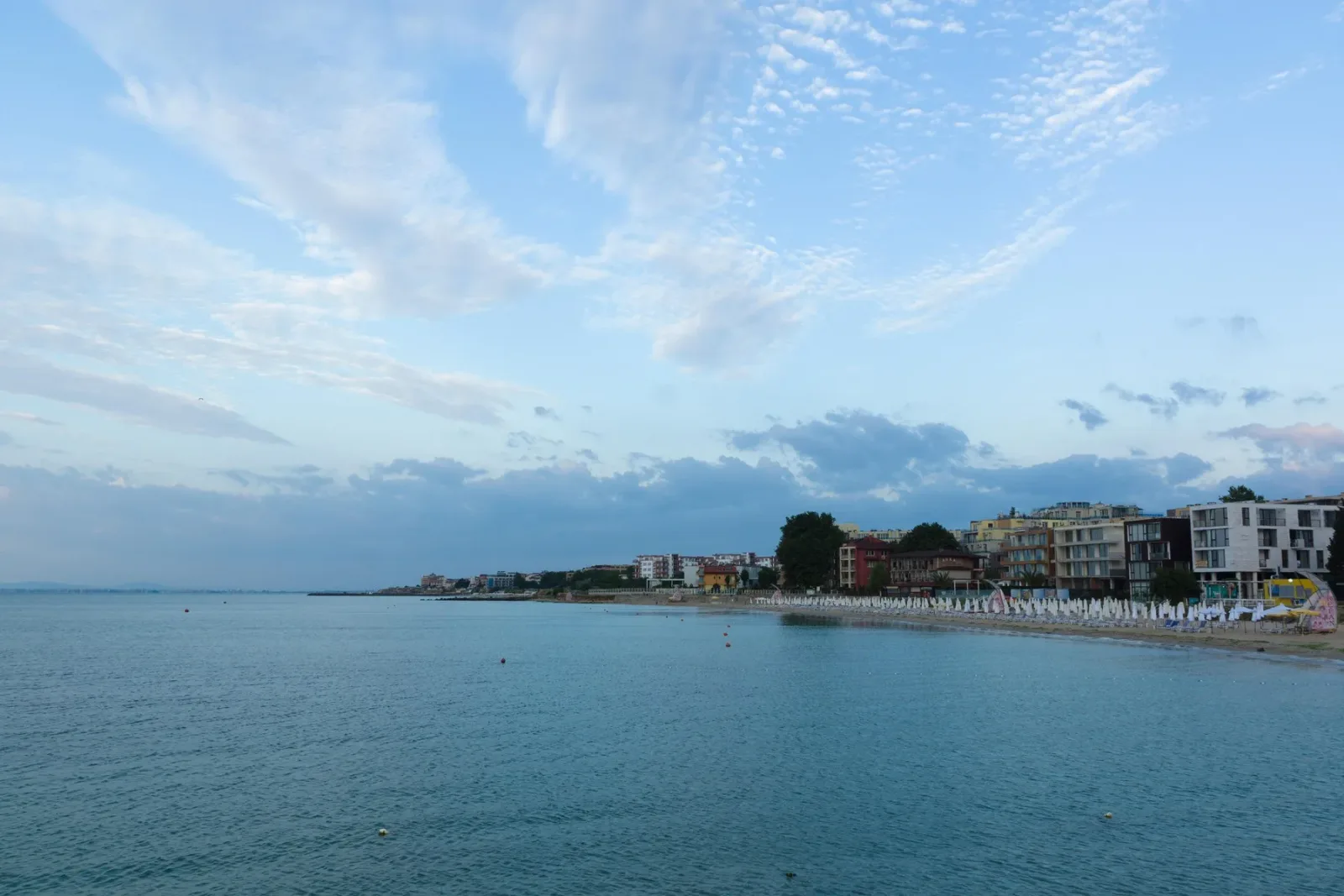 Peisaj de coastă din Bulgaria, cu clădiri și apă liniștită.