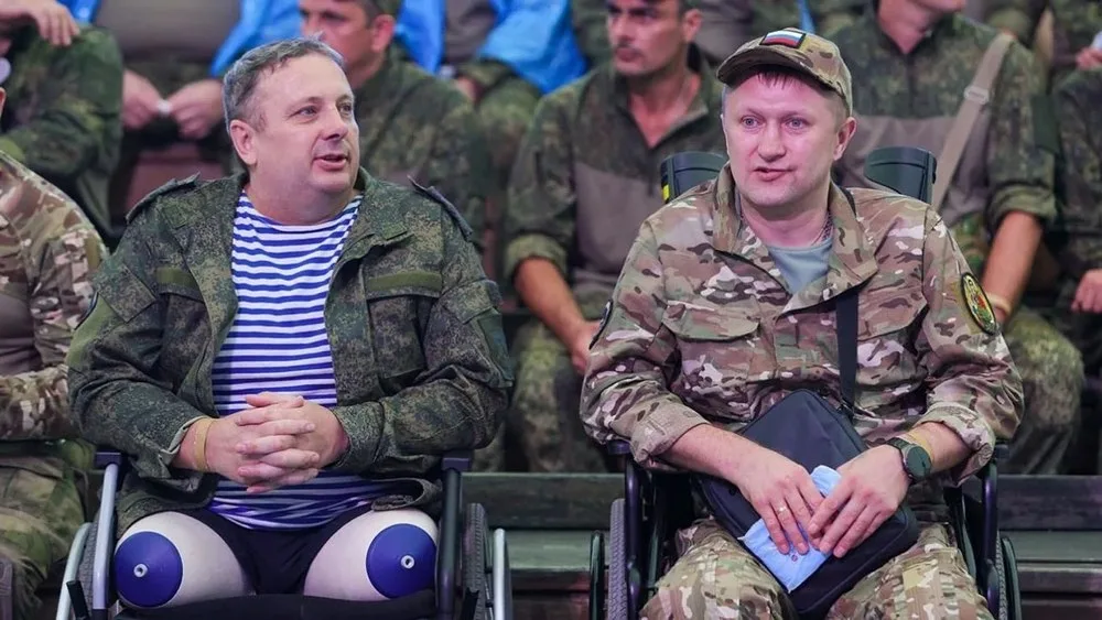 Doi bărbați în scaune cu rotile, discutând într-un mediu militar.