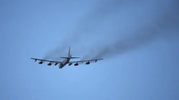 Avion militar în zbor, lăsând o dâră de fum în urma sa.