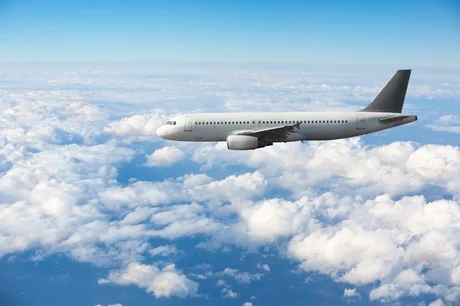 Avion zburând deasupra norilor într-un cer senin.