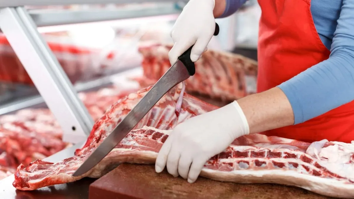Un muncitor taie carne într-un abator modern din România.