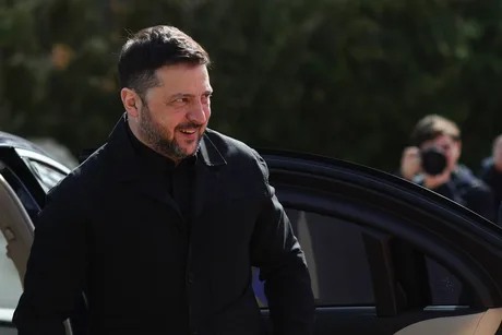 Volodimir Zelenski zâmbește în fața unei mașini, simbolizând sprijinul pentru aderarea Ucrainei la UE.