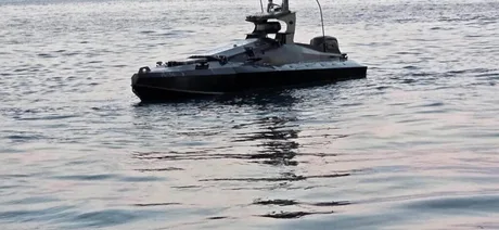 Dronă marină pe apă, reflectând lumina soarelui în fundal.
