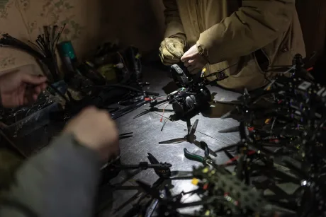 Persoane lucrând la drone într-un mediu de atelier, cu echipamente tehnice în jur.