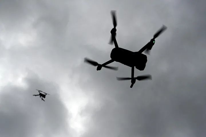 Dronă zburând pe un fundal de nori întunecați, simbolizând provocările apărării.