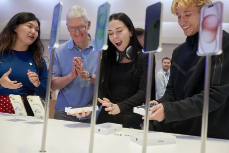 Cumpărători entuziasmați la un magazin Apple, admirând noile produse.