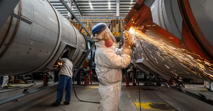 Un muncitor în echipament de protecție, lucrând la un proces industrial.
