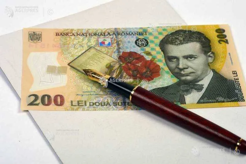 Bancnotă de 200 lei și un stilou pe un birou.
