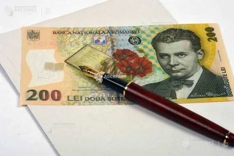 Bancnotă de 200 lei și un stilou pe un birou.