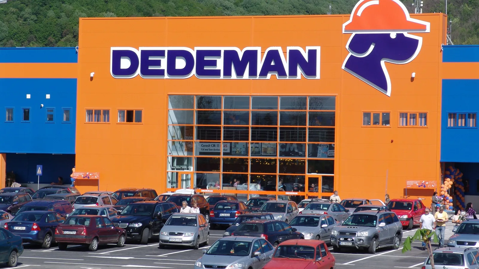 Magazin Dedeman cu parcarea plină de mașini în față.