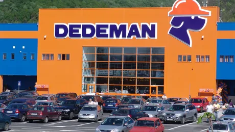 Magazin Dedeman cu parcarea plină de mașini în față.