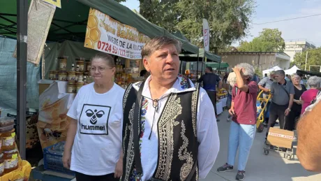Apicultor la târg, vânzând miere din Olt, cu costume tradiționale.