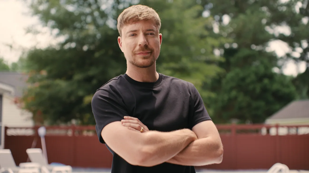 MrBeast zâmbind, cu brațele încrucișate, într-un mediu relaxat.