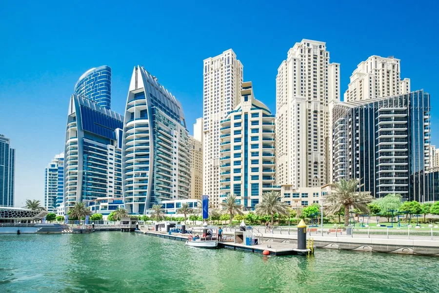 Peisaj urban din Dubai, cu clădiri moderne și apă liniștită.