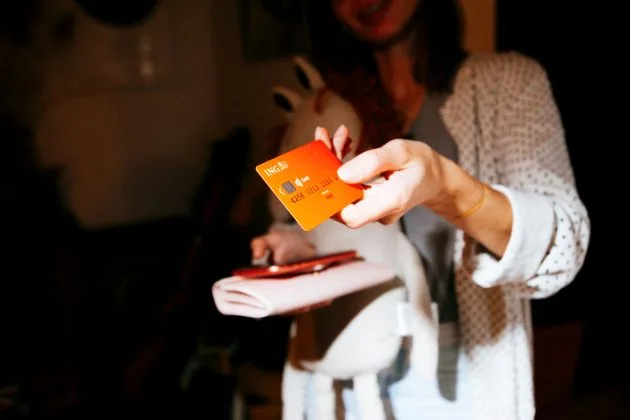 O persoană arată un card ING într-un mediu relaxat.