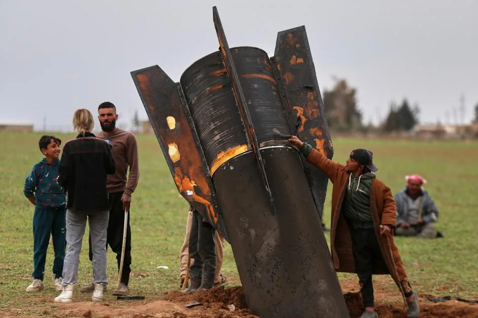 Copii se apropie de racheta căzută pe câmpul din Siria.