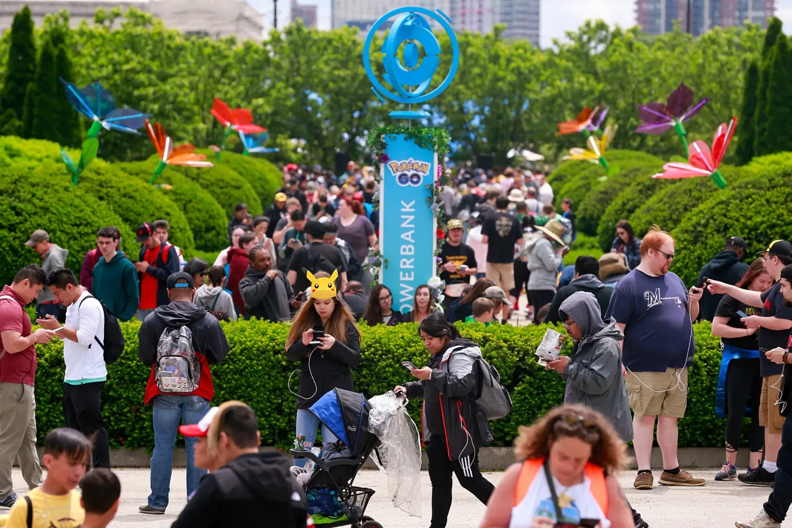 O mulțime de jucători Pokémon GO interacționând într-un parc verde, cu elemente de realitate augmentată.