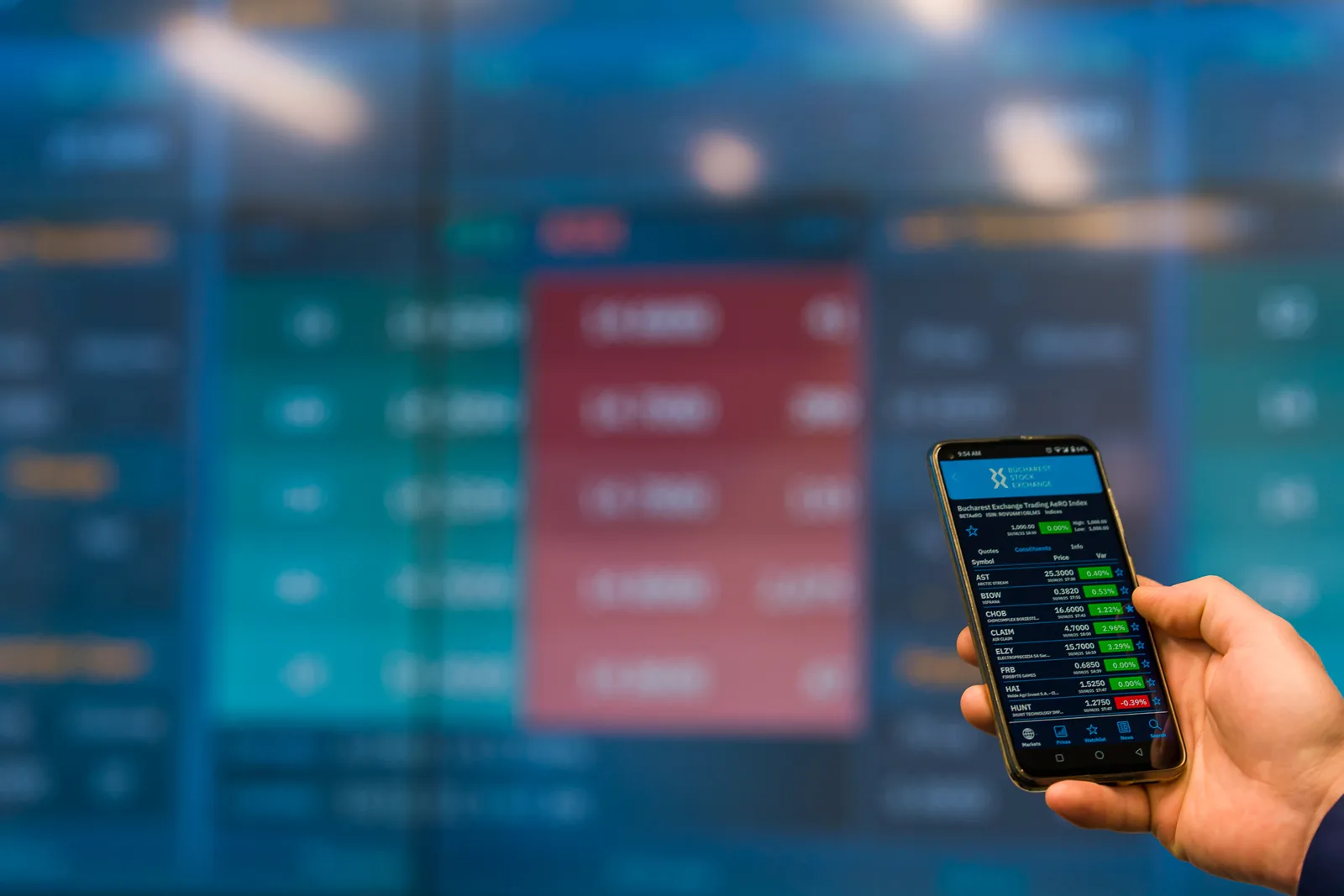 Un telefon mobil afișează date financiare pe un ecran digital.